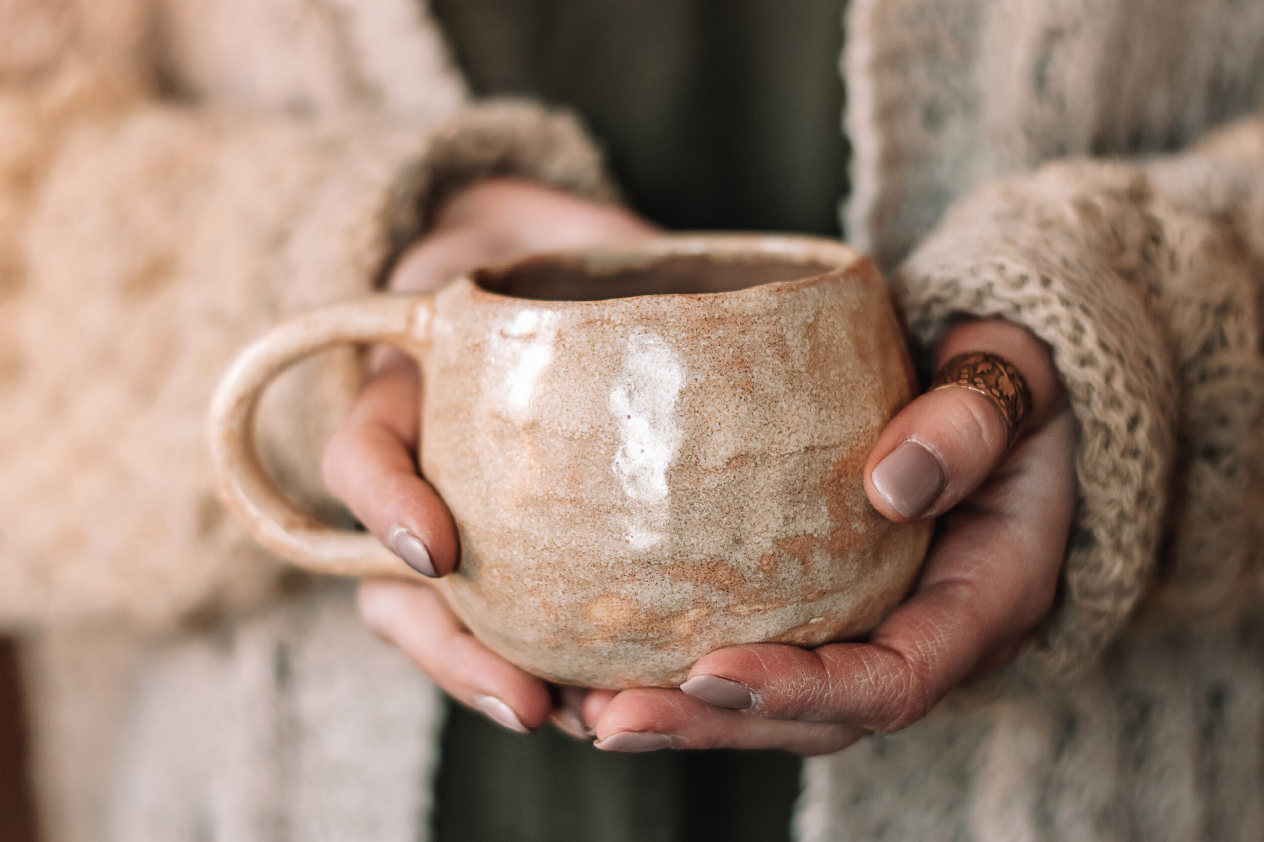Close-up of female hands holding a handmade clay mug of cacao, kawakawa benefits